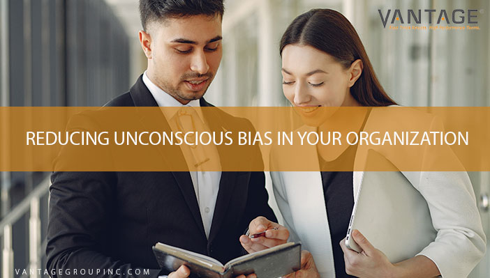 man and woman in suit talking to each other with text reading reducing unconscious bias in your organization