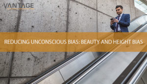 man in suit holding his cellphone with text reading reducing unconscious bias: beauty and height bias